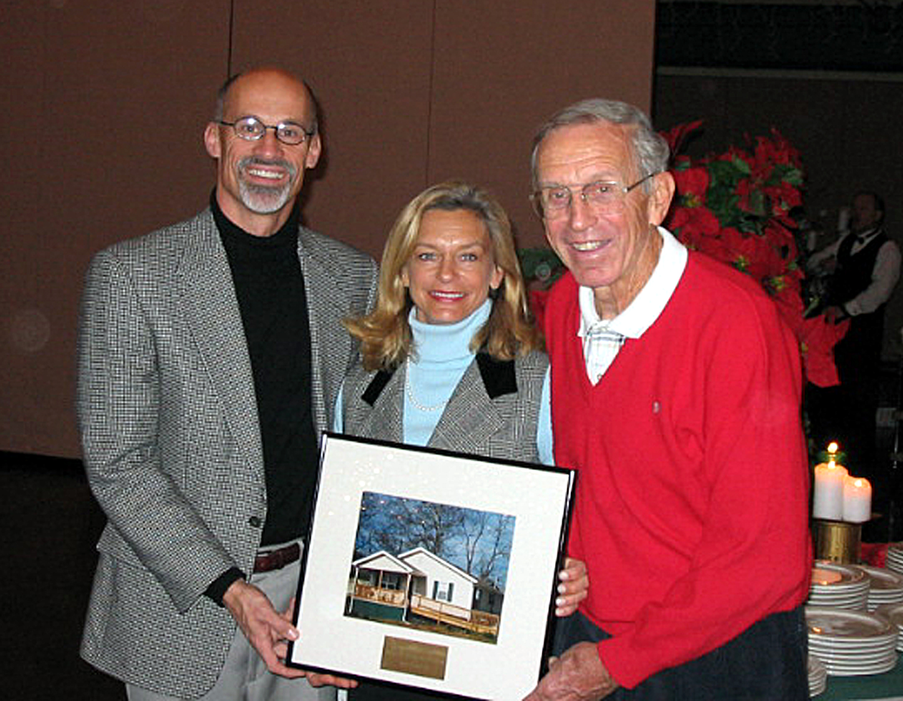 Bob Temple posing with a photo of a home that he helped build